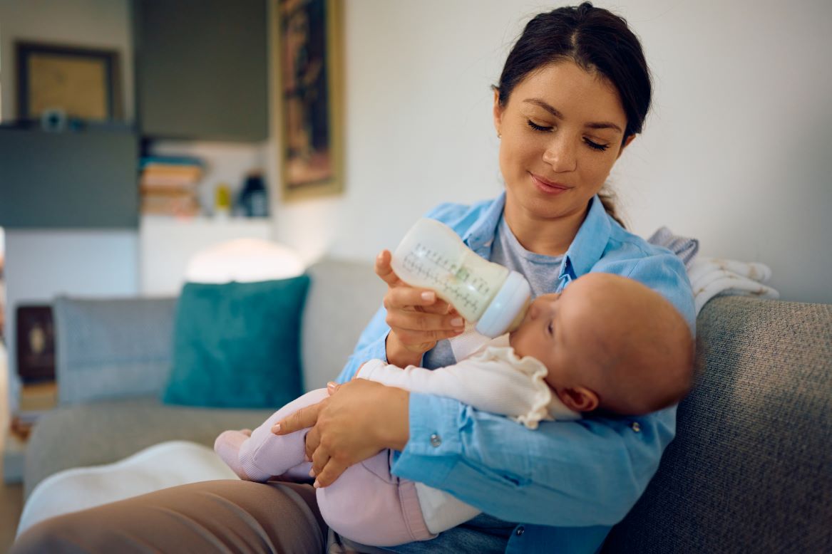 Photo shows a mother bottle feeding her baby.